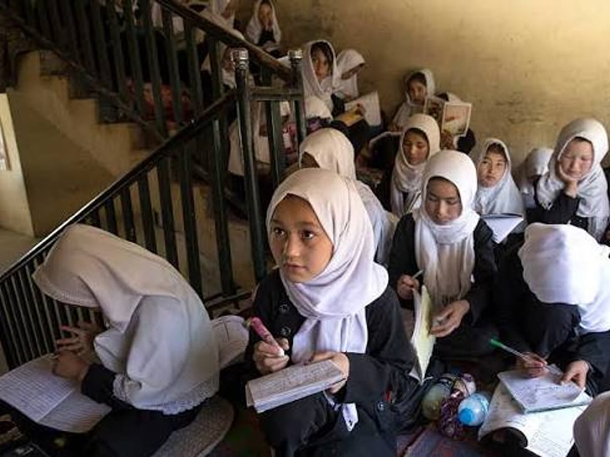 Girls in white headscarves studying together on a staircase