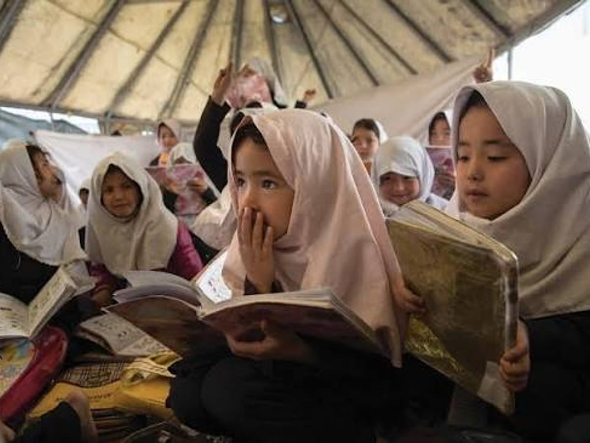 Young girls reading their schoolbooks in a tent classroom