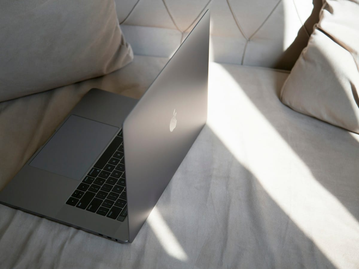 A laptop open on a bed in soft daylight